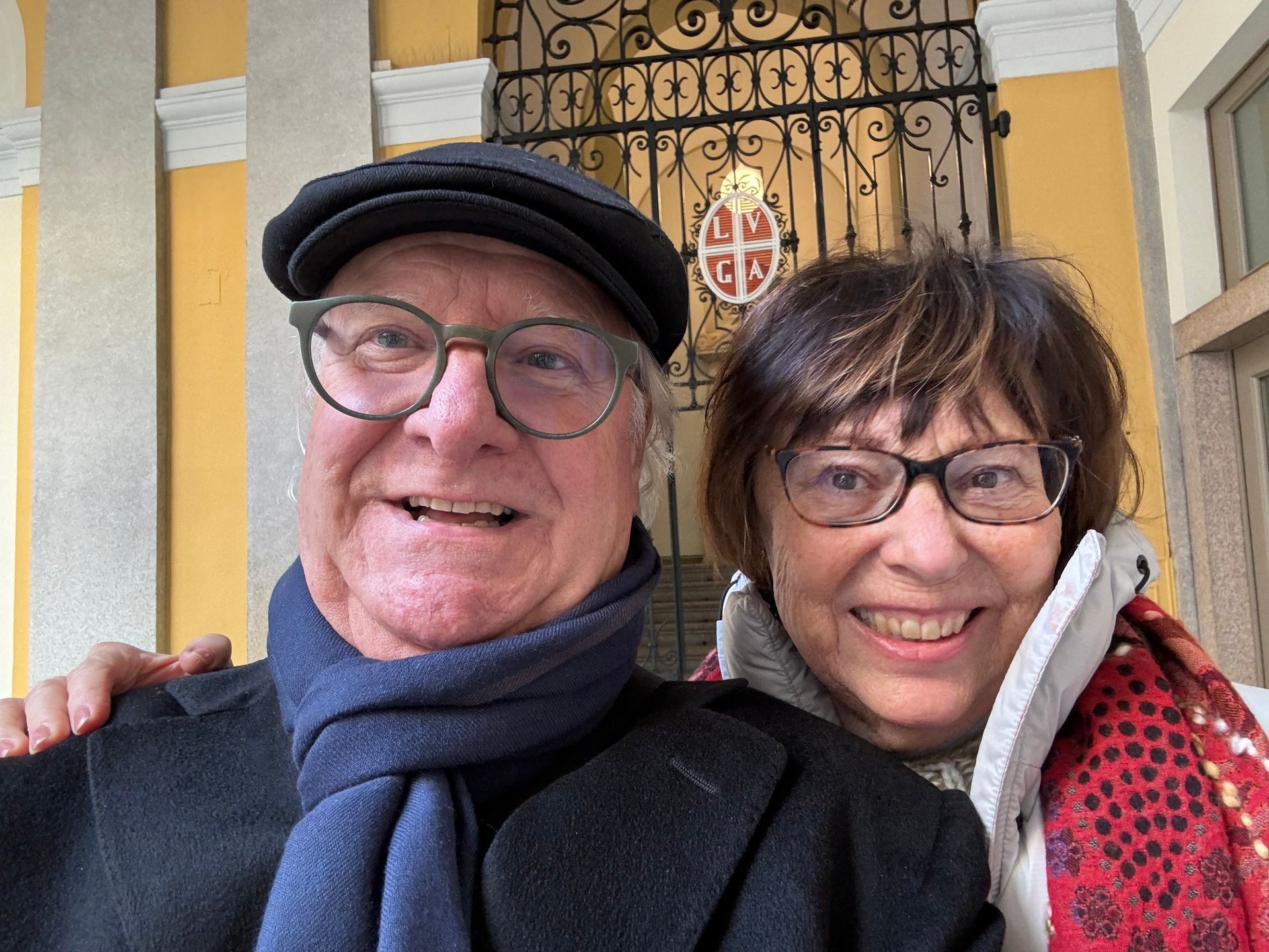 Smiling man and woman wearing glasses posing in front of ornate gate. Smiling man and woman wearing glasses posing in front of ornate gate.